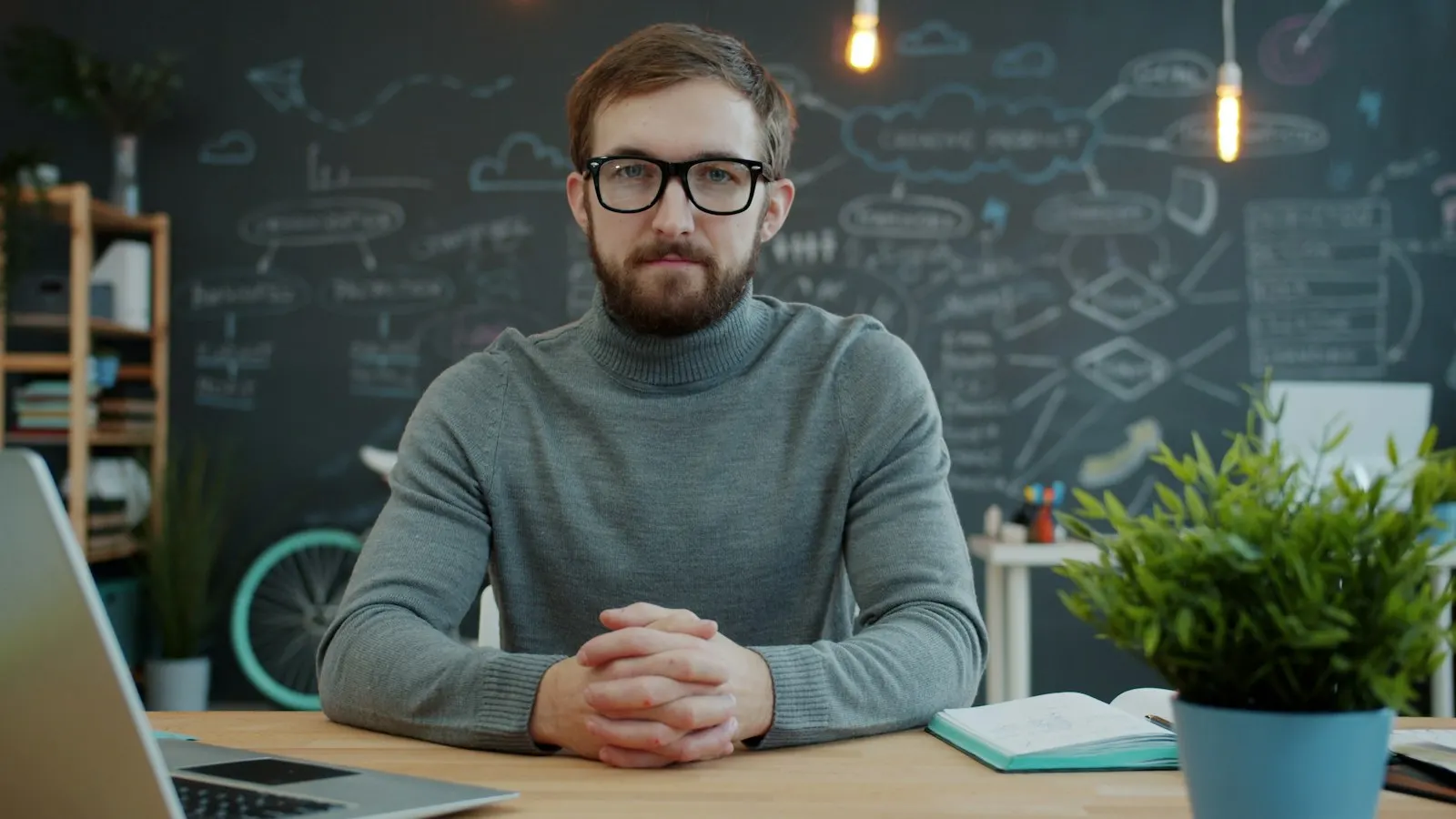 Empreendedor sentado à mesa de trabalho, com as mãos entrelaçadas